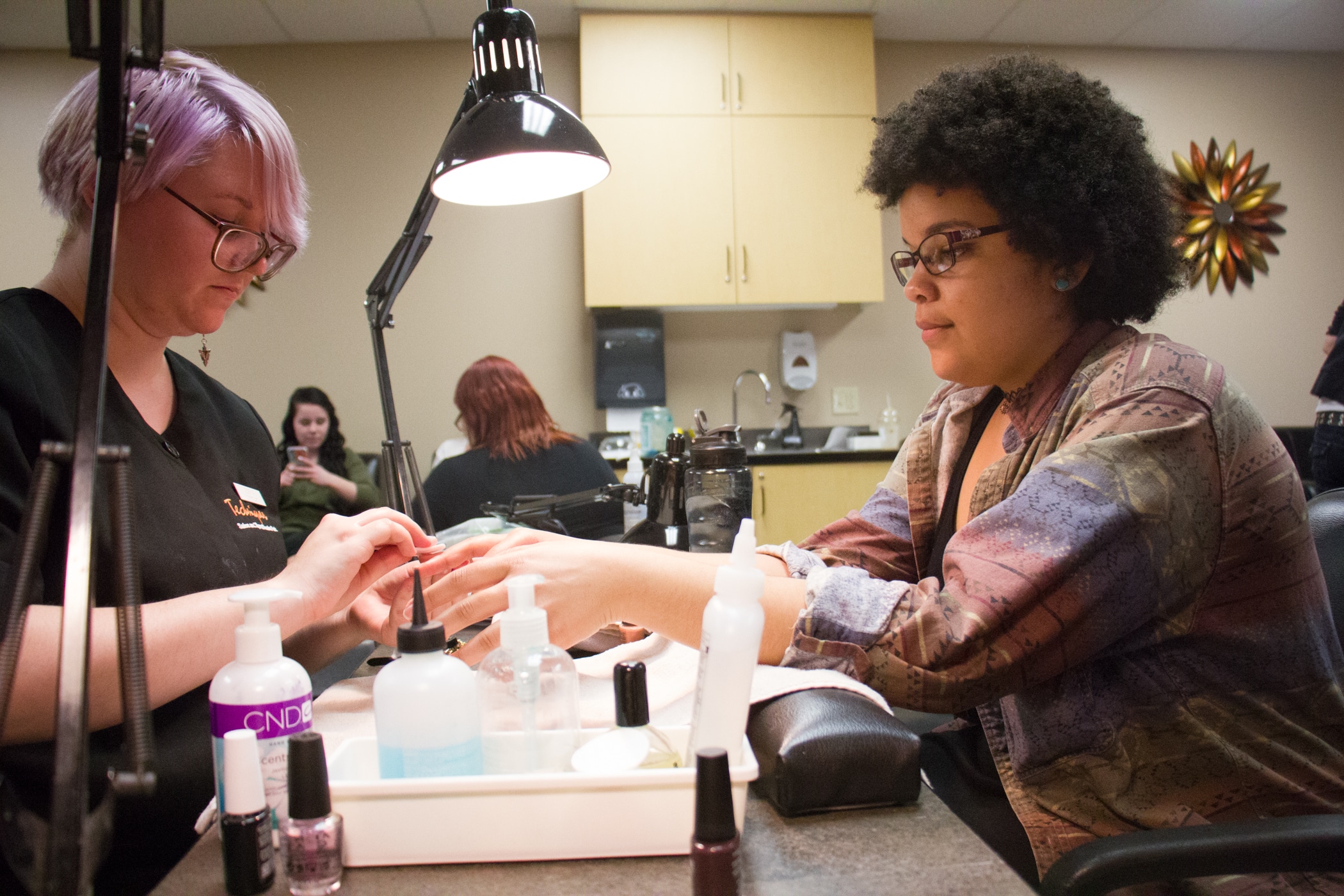 Cosmetology student giving manicure to client