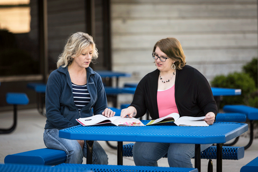 Two females looking at books at blue picnic table at Moraine Park