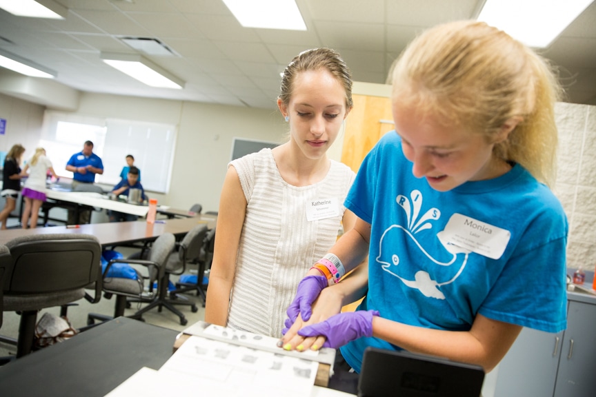 Young girls taking finger prints at Tech Knowledge College event