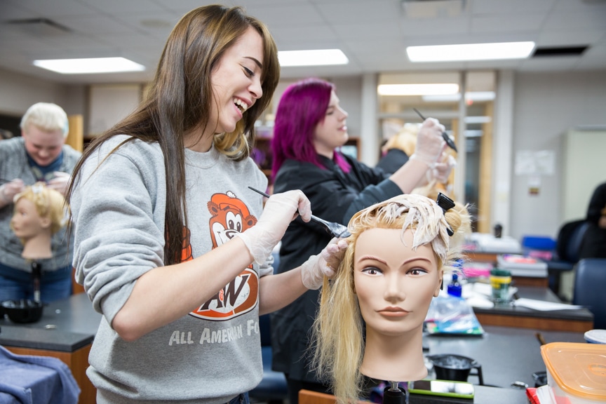 female cosmetology student coloring mannequin hair