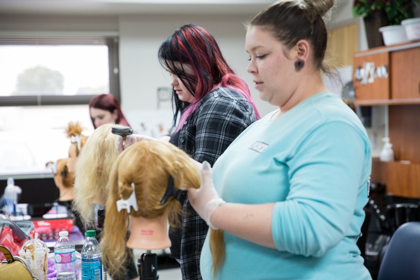 female cosmetology student coloring mannequin hair