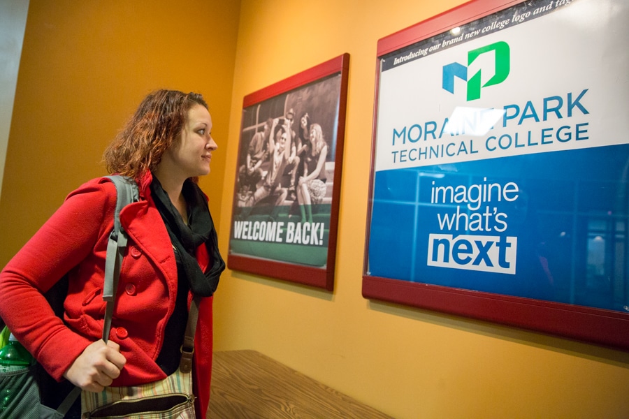 female student looking at new moraine park logo sign on wall