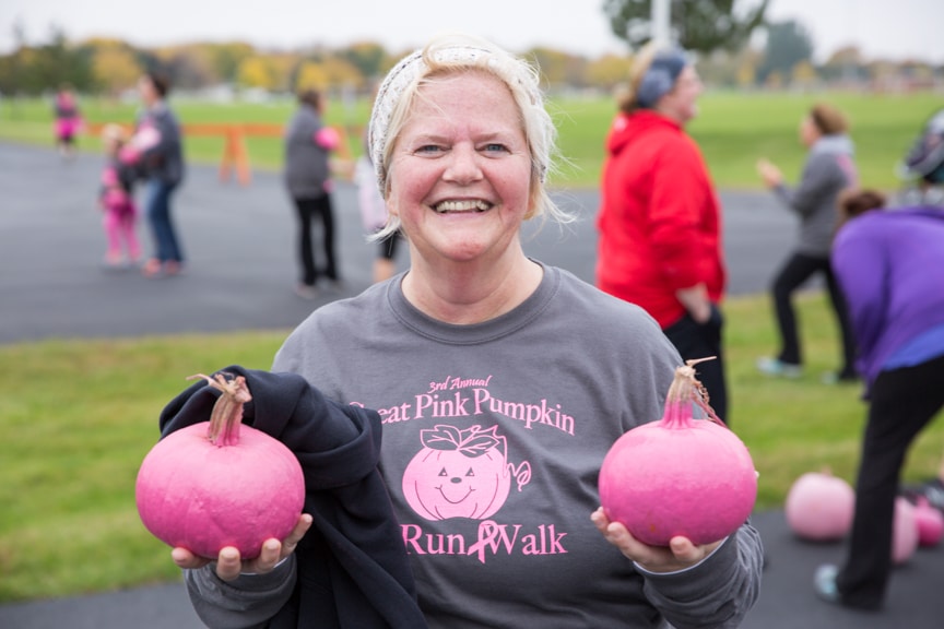 woman holds too pink pumpkins