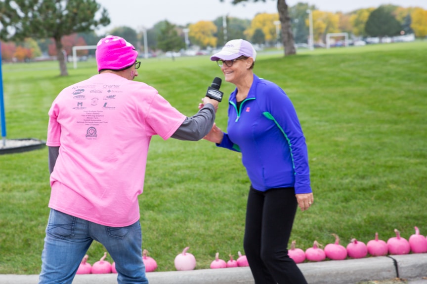 man holds microphone out to woman during pink pumpkin walk