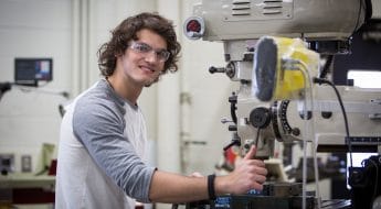 Moraine Park male student working with manufacturing machinery