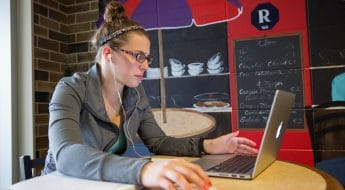 Female student working on laptop in cafeteria