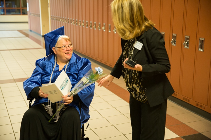 Staff member talks to graduate in wheelchair prior to Moraine Park commencement ceremony