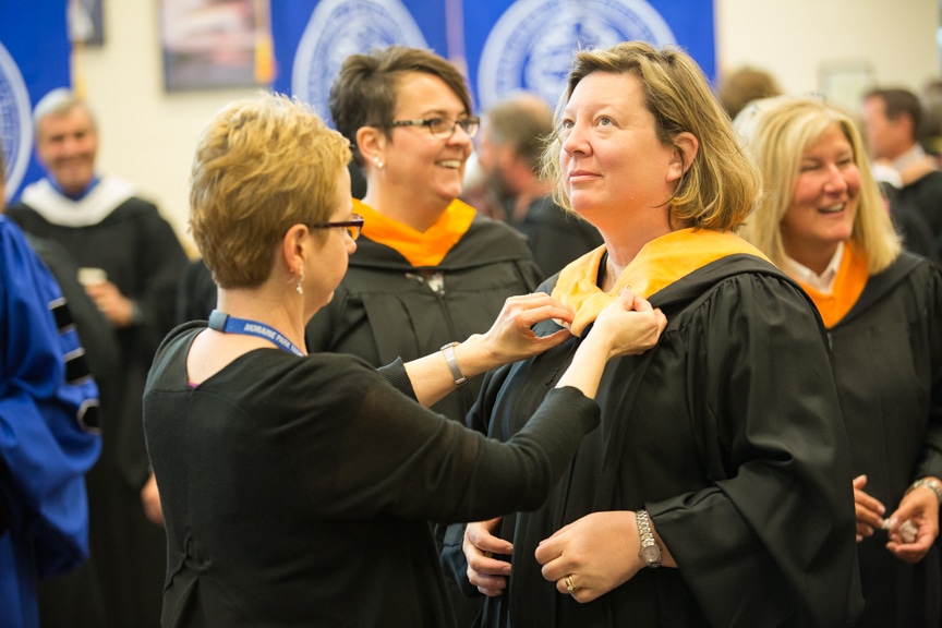 Staff putting on gowns prior to Moraine Park commencement ceremony