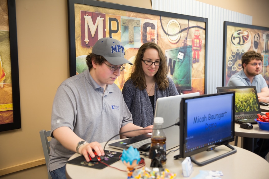 Male and female students at Moraine Park working on a computer at portfolio showcase