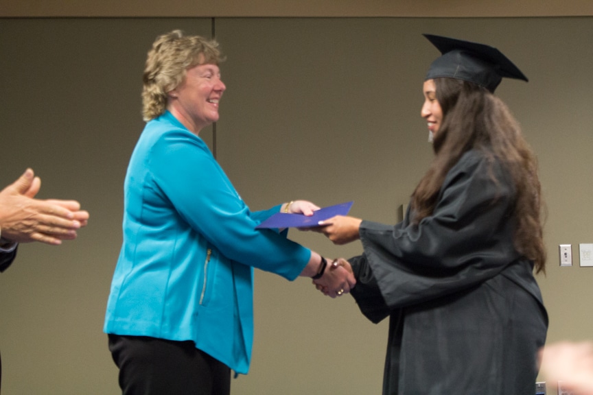 Female graduate recieves diploma and shakes Bonnie Baerwald hand at GED-HSED Gradudation Ceremony