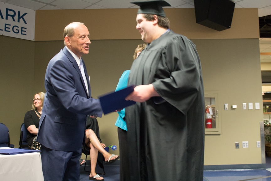 Male graduate shakes Jim Eden hand after getting diploma at GED-HSED Gradudation Ceremony
