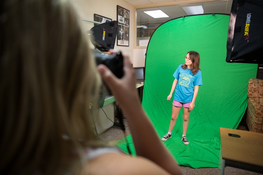 Girl photographs fellow student in front of green screen during Moraine Park summer camp activity
