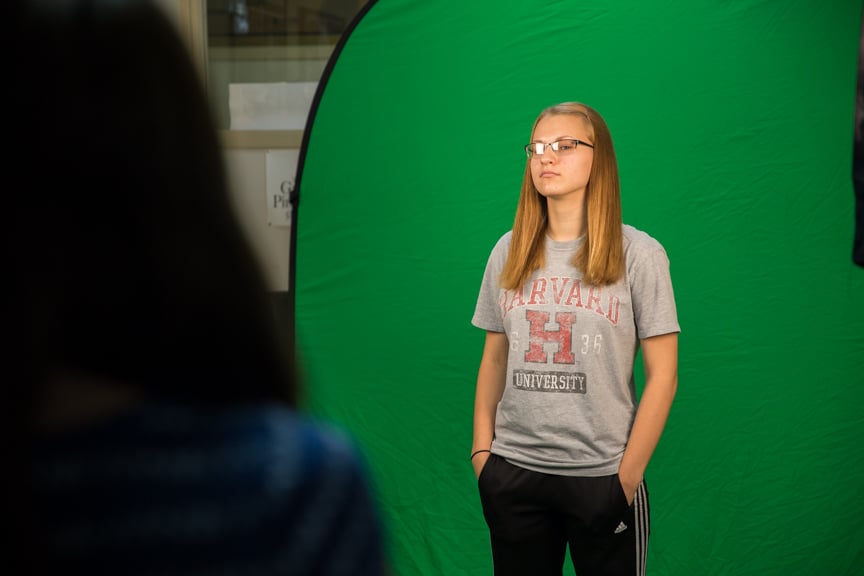 Girl poses in front of green screen during photography activity at Moraine Park summer camp