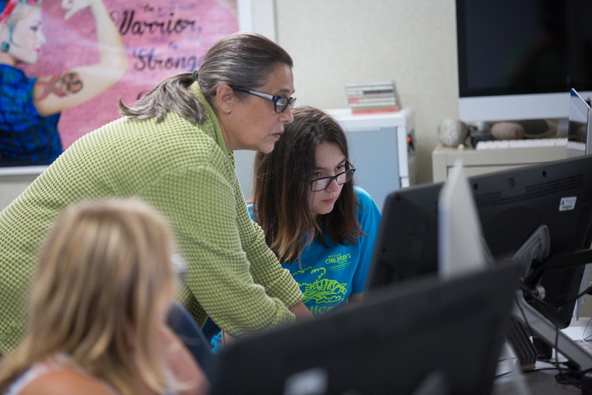 Instructor helps girl with graphic design project on iMac computer at Moraine Park summer camp