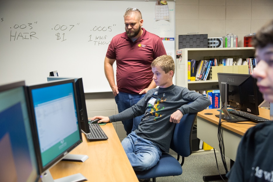 Boy working on computer with instructor in classroom at Moraine Park
