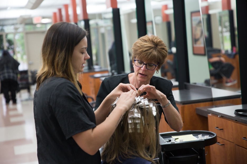 Instructor Eileen Bouchard inspects student haircut in cosmetology class