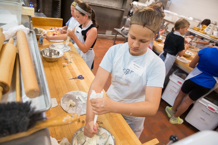 Girl works on icing technique during culinary activity at Moraine Park TKC summer camp