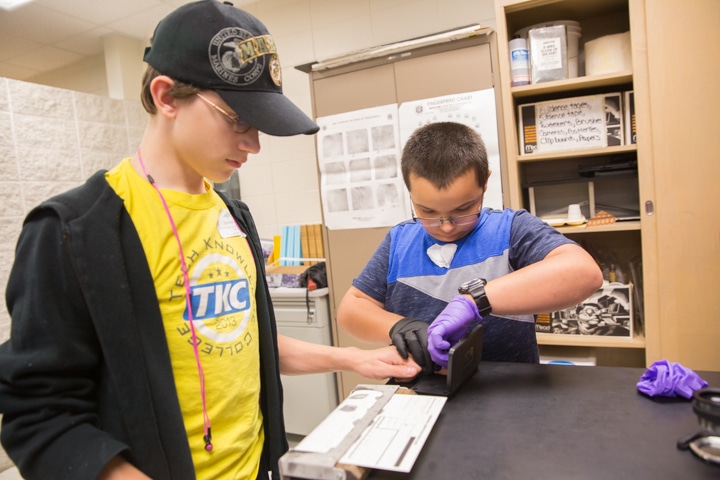 Two boys do fingerprint activity with paper and ink at Moraine Park Tech Knowledge College