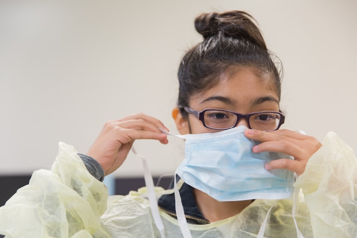 Girl begins to put on surgical mask during activity at Moraine Park TKC summer camp
