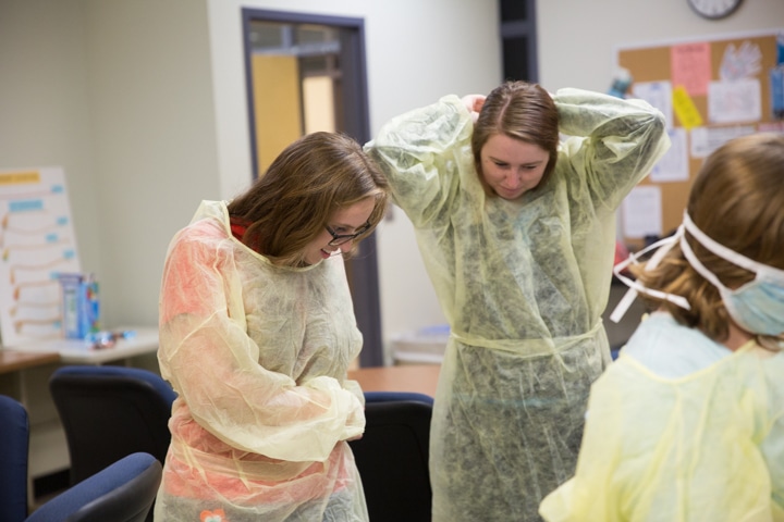 Girls put on surgical gowns during Moraine Park Tech Knowledge College
