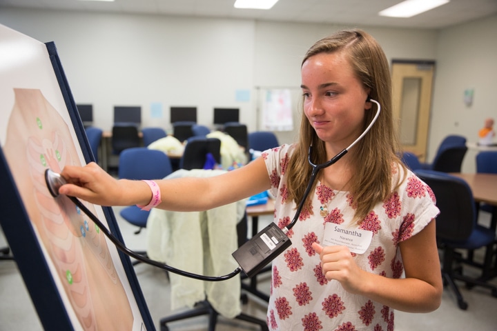 Girl uses stethoscope to hear simulated chest noises at Moraine Park Tech Knowledge College