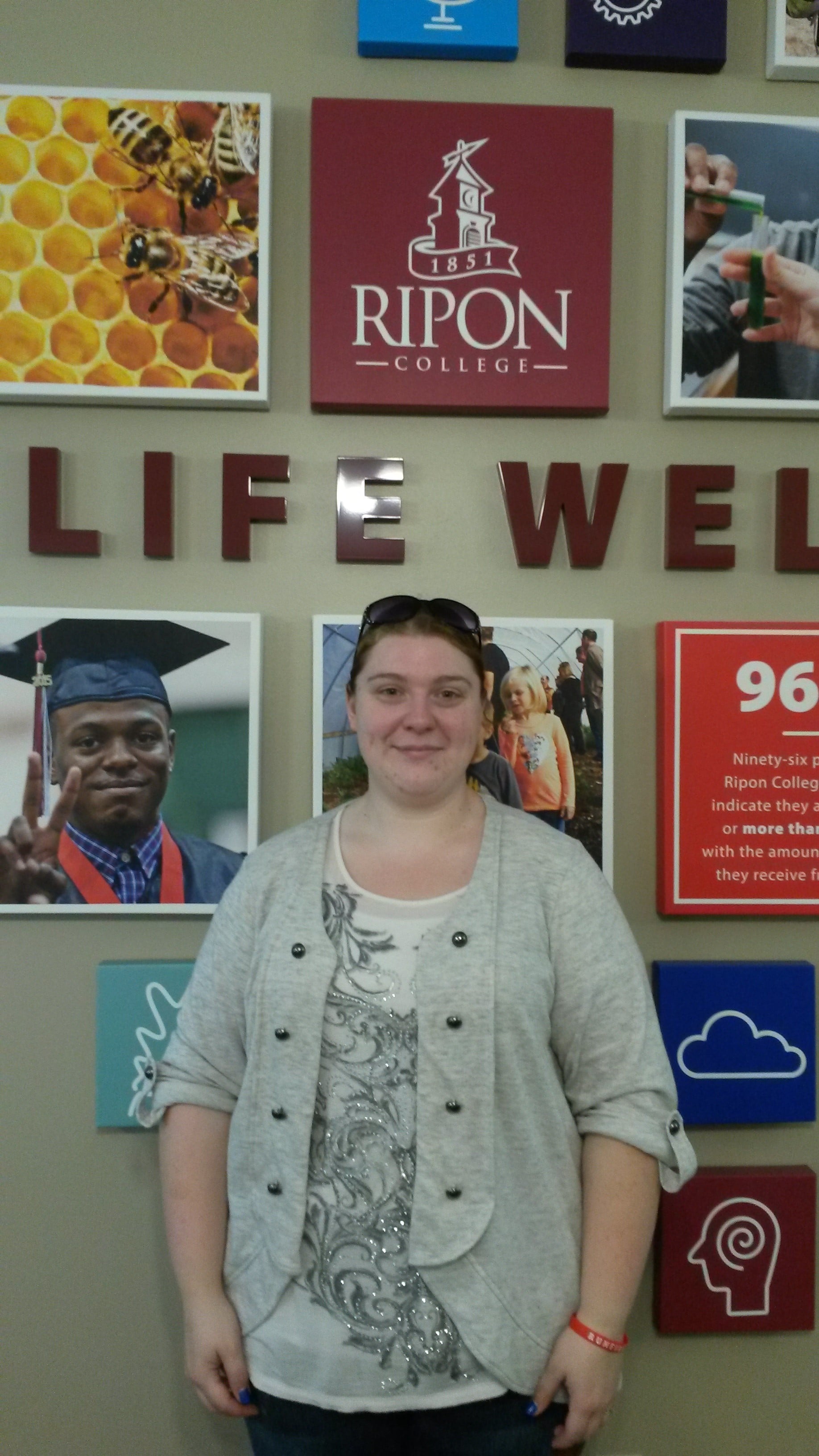 Becky Weyer, standing in front of a Ripon College display wall, during her tour of campus.