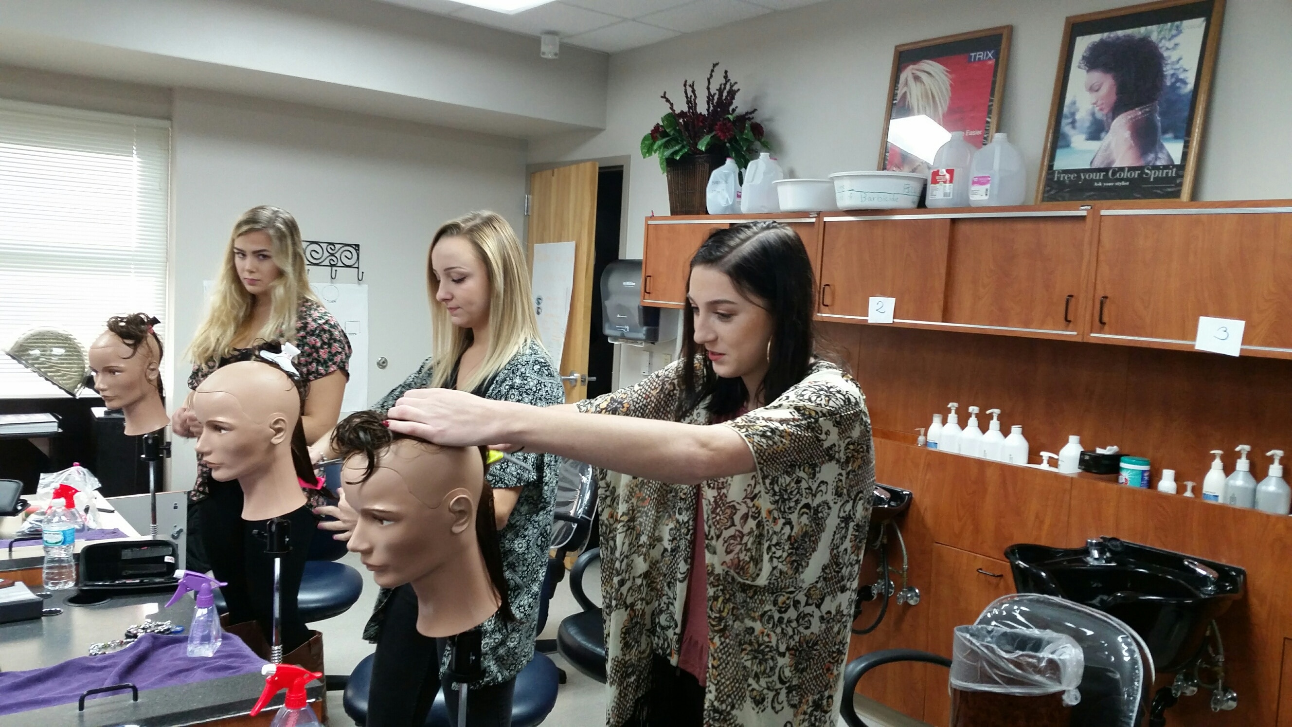 female cosmetology students working on mannequins 