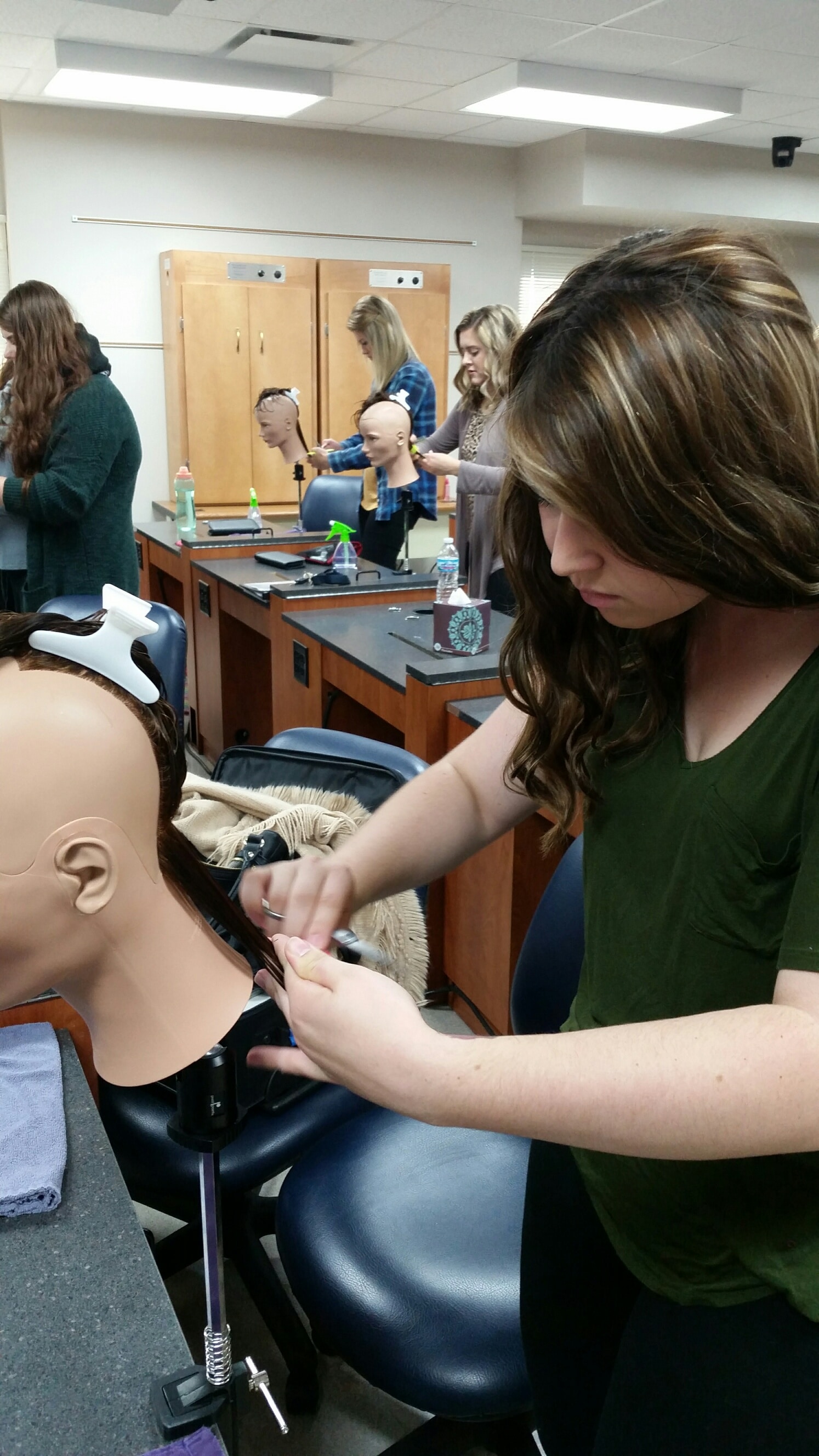 cosmetology students working on mannequins 