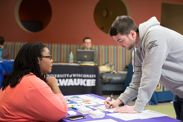 male student fills out paperwork at transfer fair