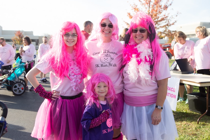 three women and one child wearing pink wigs
