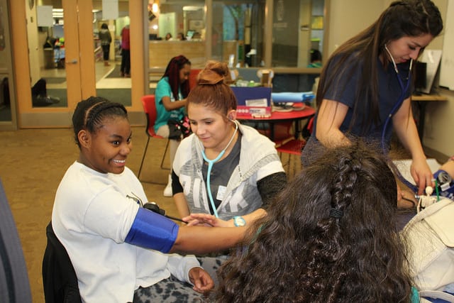 Moraine Park Medical Assistant student checking the blood pressure of a teenage girl. 