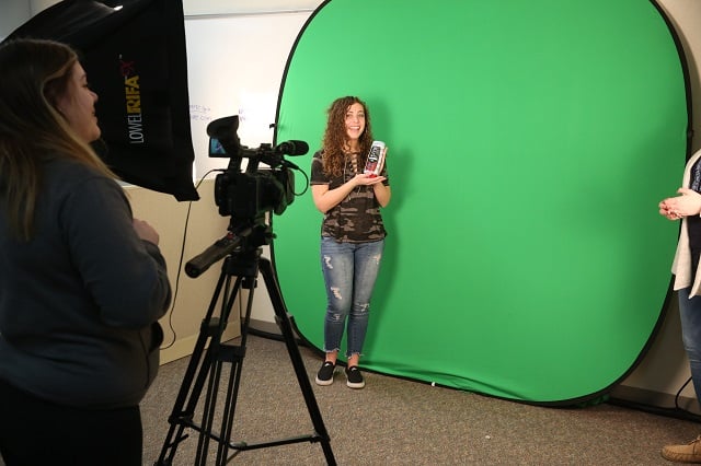 Marketing students working with a green screen to shoot a commercial.