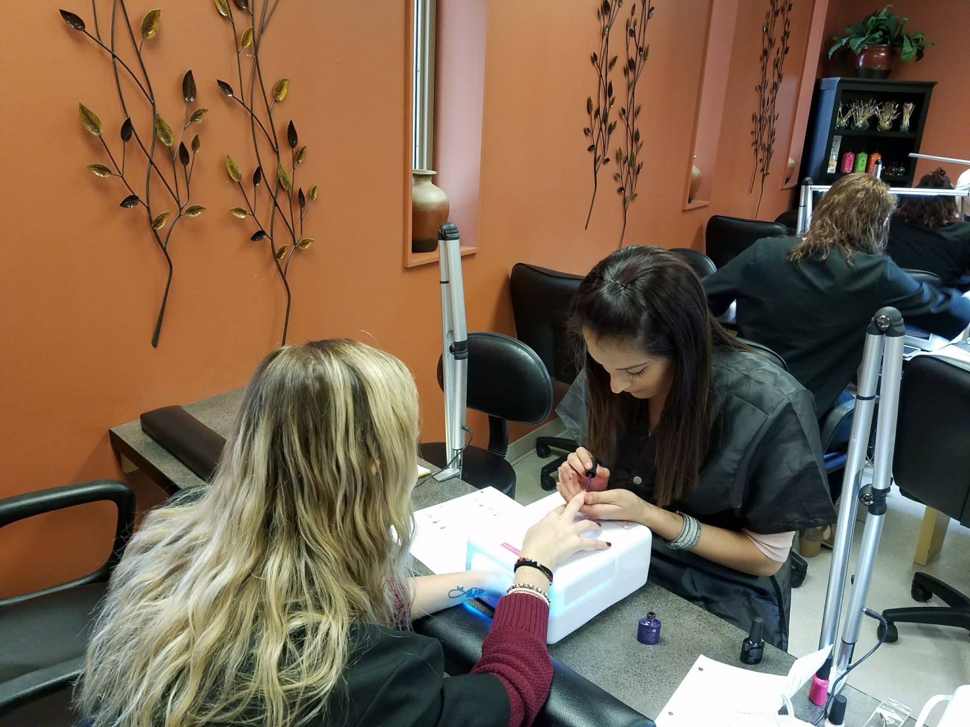 Cosmetology student performing nail service on fellow student