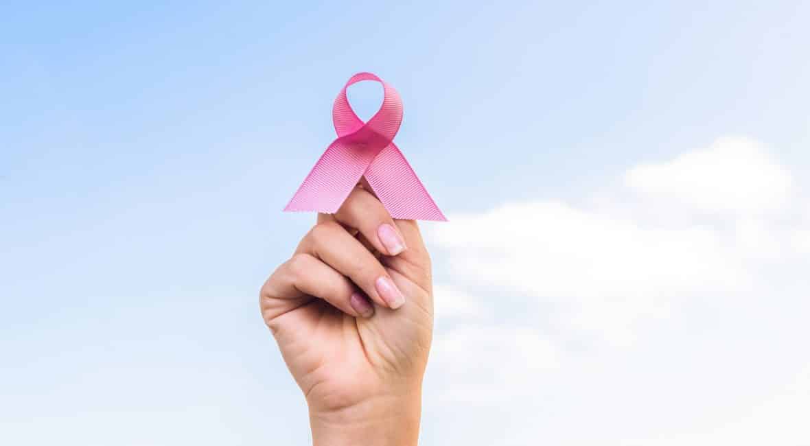 close-up partial view of hand holding breast cancer awareness ribbon