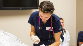 female nursing student in scrubs with stethoscope around her neck.